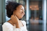 Photo of young woman scratching her neck, suffering from atopic dermatitis or psoriasis