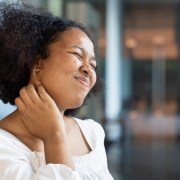 Photo of young woman scratching her neck, suffering from atopic dermatitis or psoriasis